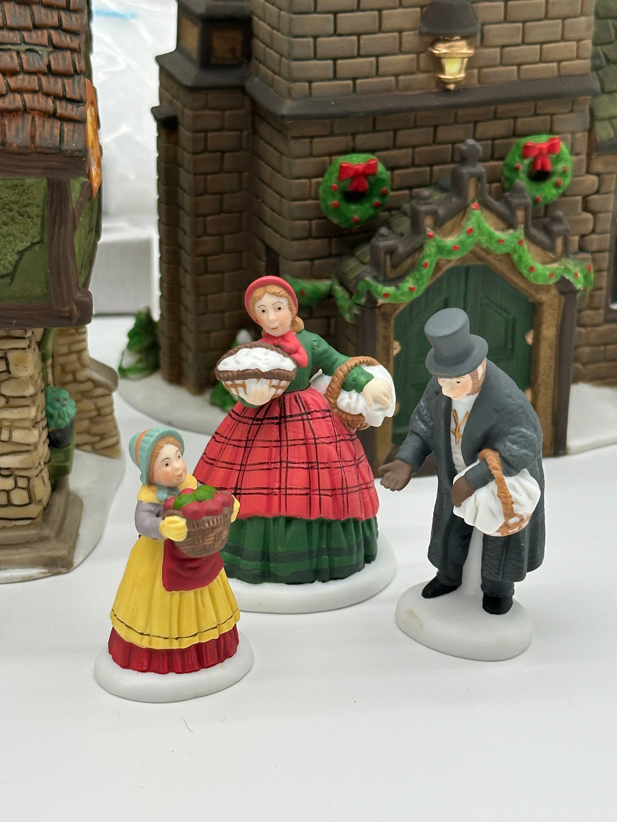 The Spirit of Giving figures: a young lady with a pie, a girl with a basket and the Rector, in front of Sudbury Church