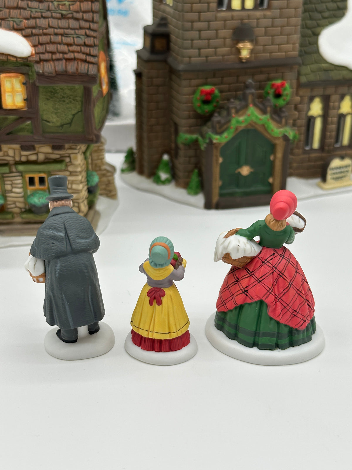 The three Spirit of Giving figures seen from behind, with the Rectory and church behind them